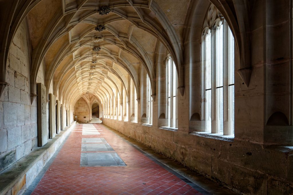 Galerie voûtée d'un cloître monastique baigné de lumière