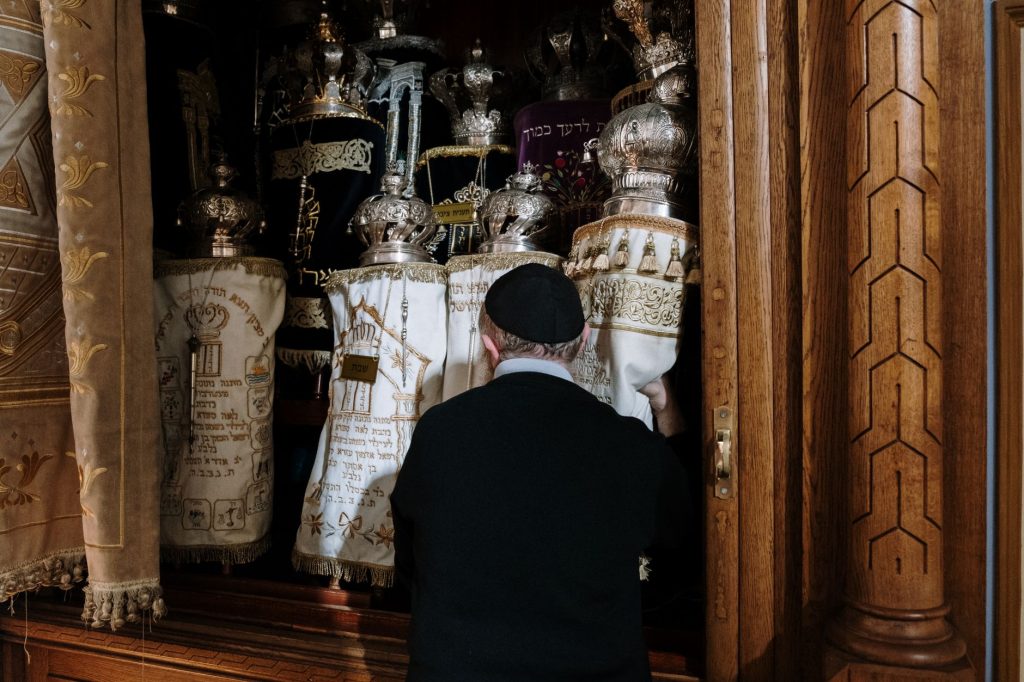 Officiant tenant des rouleaux de la Torah devant l’arche sainte d’une synagogue