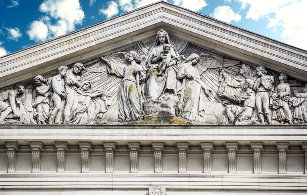 Bas-relief sculpté sur la façade d'une église, figures religieuses sous un ciel lumineux