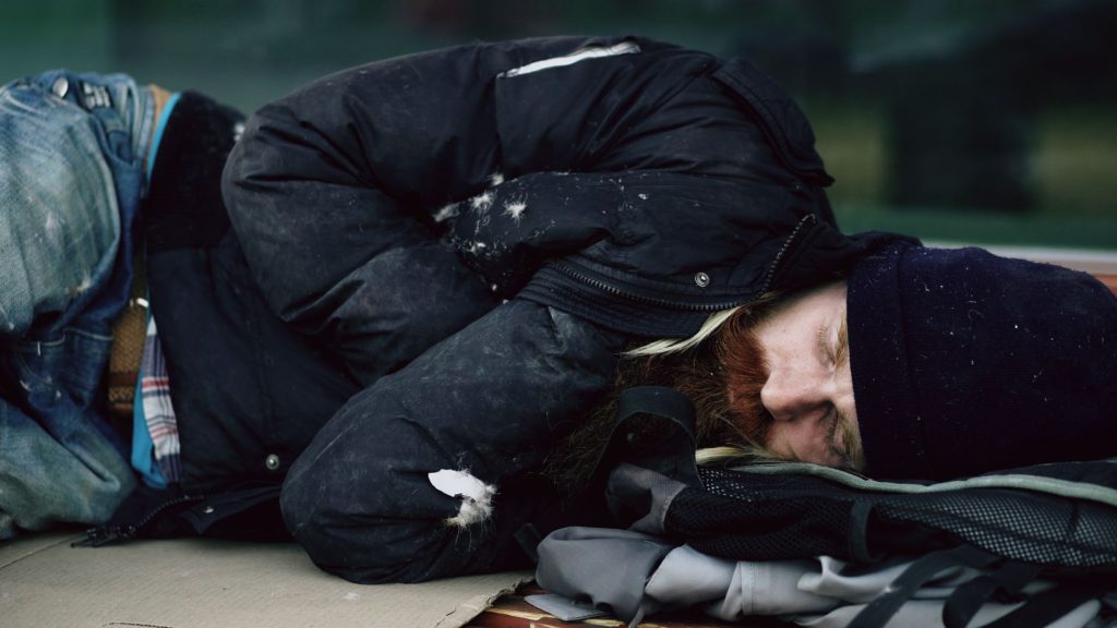 Personne sans abri dormant dehors sur des cartons par temps hivernal en ville