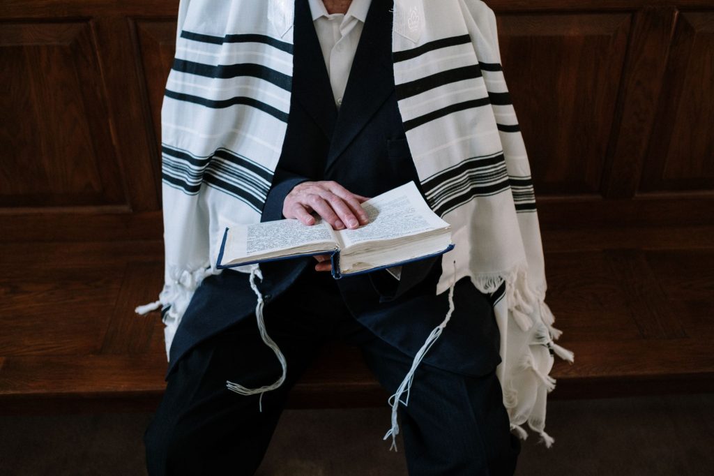 Fidèle revêtu du talith lisant le siddour dans une synagogue