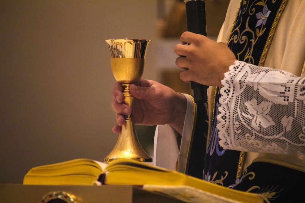 Calice d’or élevé par un prêtre pendant la célébration eucharistique