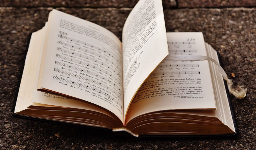 Ancien hymnaire ouvert posé sur une surface en pierre, présentant des notes de musique et un texte liturgique