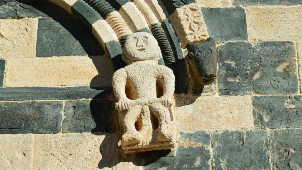 Sculpture de pierre médiévale insérée dans un mur d’église, témoin du savoir-faire lapidaire