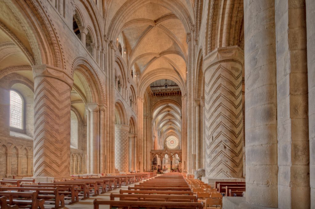 Nef gothique d’une cathédrale anglaise aux arcades massives, évoquant l’architecture des grands sanctuaires de pèlerinage médiévaux