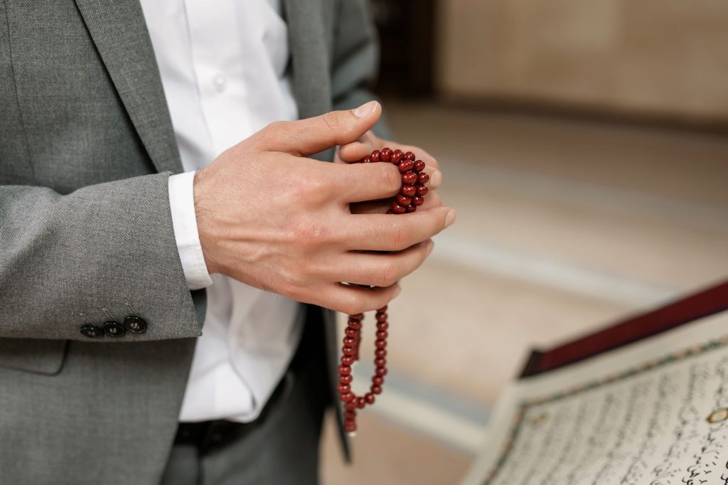Mains tenant un chapelet de prière (tasbih)