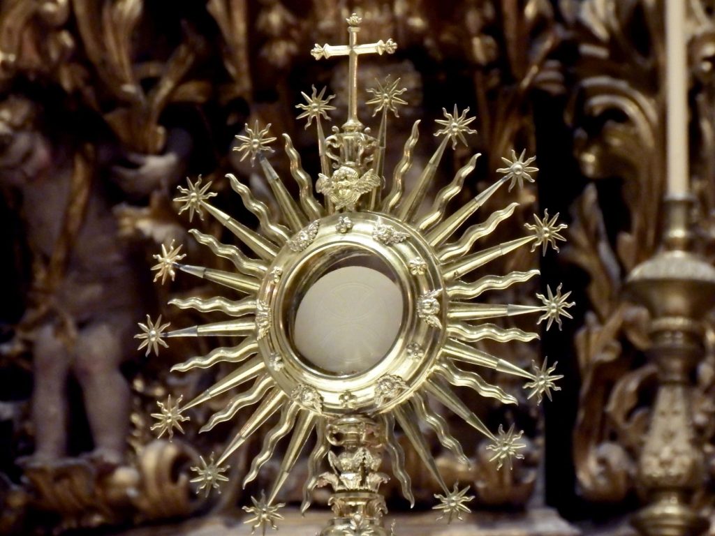 Ostensoir doré en forme de soleil dans une église catholique, exemple d'orfèvrerie liturgique destinée à rendre visible le sacré
